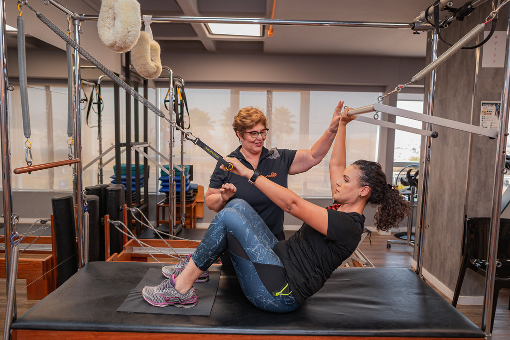Fisioterapeuta orientando paciente durante exercício em clínica de fisioterapia